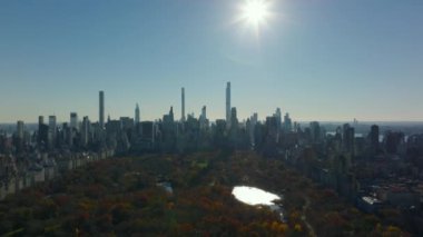 Central Park ve şehir merkezindeki gökdelenlerin panoramik görüntüleri güneşe karşı. Arka planda sonbahar manzarası. Manhattan, New York City, ABD.