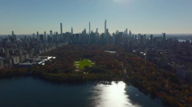 Central Park 'taki su deposunun, softball sahalarının ve sonbahar ağaçlarının yüksek binalarla çevrili havadan çekilmiş görüntüleri. Manhattan, New York City, ABD.