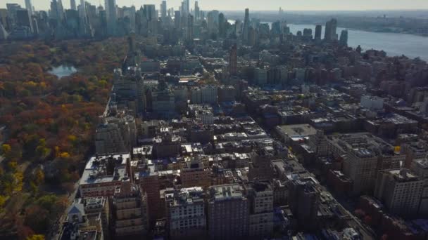 町の複数階建ての建物の空中ビュー セントラルパークのカラフルな秋の木 背景には近代的な高層タワー 米国ニューヨーク市マンハッタン — ストック動画