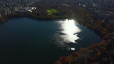 Central Park 'ın sonbaharında parlayan su yüzeyinin havadan görünüşü. Modern iş gökdelenlerini gözler önüne serin. Manhattan, New York City, ABD.