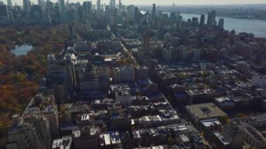 İleri, Central Park yakınlarındaki yerleşim yerlerindeki binaların üzerinden uçuyor. Gökdelenleri olan bir gökyüzü. Manhattan, New York City, ABD.