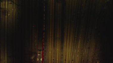 Geceleri kötü aydınlatılmış demiryolu raylarının tepeden tırnağa manzarası. Yanlara park edilmiş trenlerin üzerinde uç. Kopenhag, Danimarka.