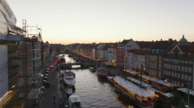 Alacakaranlıktaki Nyhavn 'ın güzel bir çekimi. Turist caddesinde parlak renkli evler ve dalgalı kanallara demirlenmiş tekneler. Kopenhag, Danimarka.