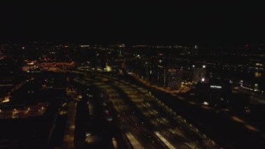 Gece şehrinin havadan panoramik görüntüsü. Aydınlanmış binalarda arabalar ve trenler geziyor. Kopenhag, Danimarka.