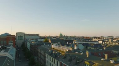 Şehir merkezindeki binaların üzerinden öğleden sonra ilerliyorlar. Çatıların üstünde alçak uçuş, büyük kilise kubbesine doğru gidiyor. Kopenhag, Danimarka.