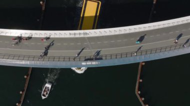 Bisikletçi ve yaya köprüsünün altından geçen teknenin en üstteki görüntüleri. Şehirdeki modern tasarım taşıma altyapısı. Kopenhag, Danimarka.