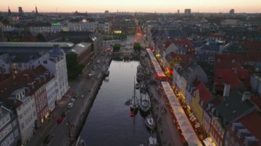 İleri, Nyhavn 'ın üzerinden uçuyor. Şehirdeki barları ve restoranları su kanalı olan parlak renkli evler. Kopenhag, Danimarka.