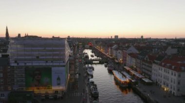 Nyhavn 'ın havadan yükselen görüntüleri. Su kanalı ve gezinti güvertesi olan ünlü bir cadde. Su yüzeyi alacakaranlık gökyüzünü yansıtıyor. Kopenhag, Danimarka.