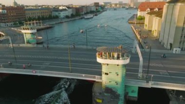 İnsanlar Knippel Köprüsü 'ndeki gözcü kulesinden suyun tadını çıkarıyorlar. Yukarı doğru eğilince, altın saat içinde iç rıhtım boyunca binalar ortaya çıkıyor. Kopenhag, Danimarka.