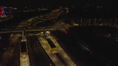 Gece kentinde tren istasyonu platformlarının ve demiryolunun yüksek açılı görüntüsü. Yolcu treninden kalkış takibi devam ediyor. Kopenhag, Danimarka.