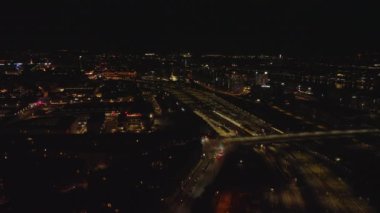 Gece şehrinin üzerinde uç. Aydınlatılmış binaların, ulaşım altyapısının, karayolunun ve demiryolunun havadan görüntüsü. Kopenhag, Danimarka.