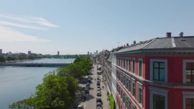 İleride caddenin üstünde ve göl kıyısında binalar var. Şehirde şehir gelişimi. Kopenhag, Danimarka.