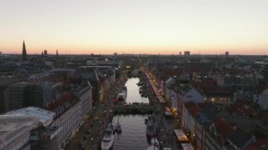 Alacakaranlıktaki şehir manzarası. Forvetler Nyhavn 'ın üzerinde uçuyor, kalabalık turist caddeleri eğlence dolu. Kopenhag, Danimarka.