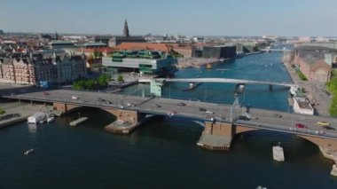 Yoğun yol köprüsü, zarif modern bisiklet ve su yüzeyindeki yaya köprüsünün havadan görünüşü. Şehirdeki binaların panoramik manzarası. Kopenhag, Danimarka.