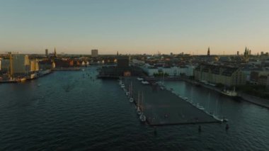 Vashtis İskelesi 'nin üzerinde yelkenli tekneleriyle ilerliyorlar. Gün batımında su kanalı boyunca bina görüntüsü. Kopenhag, Danimarka.