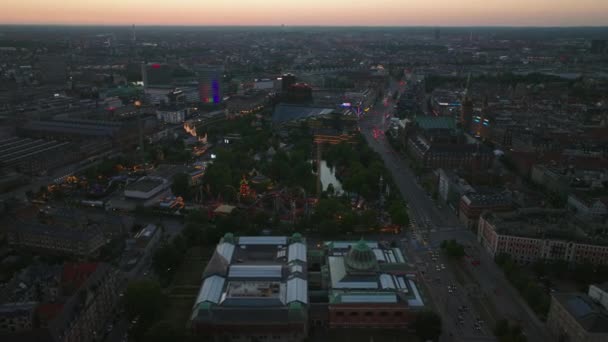 ティヴォリ庭園遊園地にある照明付きのアトラクション 夕暮れ時の街の空中ビュー デンマークのコペンハーゲン — ストック動画
