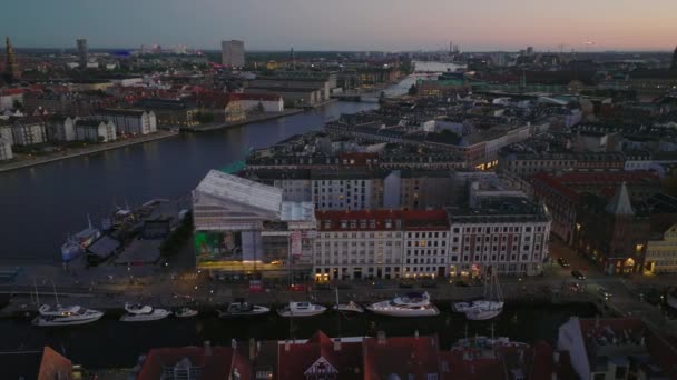夜の街の美しい空撮 歴史的な都市中心部の建物や夕暮れ時の水の運河 デンマークのコペンハーゲン — ストック動画