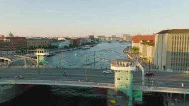 Şehrin su yüzeyine yayılan köprünün üzerinden uç. Su kanalında seyreden tekneler öğleden sonra limanda gezen insanlar. Kopenhag, Danimarka.