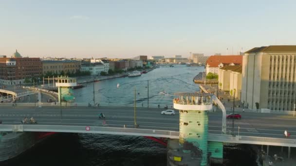 町の水面に架かる橋を飛び越える 水上運河を航行するボートは 人々がウォーターフロントを散歩することで午後遅くを楽しんでいます デンマークのコペンハーゲン — ストック動画