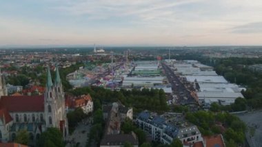 Alacakaranlıkta şehir merkezindeki binaların üzerinden uç. Kalabalık Oktoberfest bölgesinin, ünlü ve popüler bira ve halk festivalinin hava kaydırak ve pan görüntüleri. Münih, Almanya.
