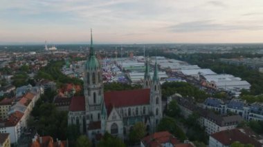 Alacakaranlıktaki şehrin havadan panoramik görüntüsü. Büyük gotik kilisenin üzerinden uçup Theresienwiese 'i gösterirken ziyaretçiler Ekim Festivali' nin atmosferinin ve biranın tadını çıkarıyorlar. Münih, Almanya.