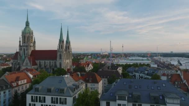 都市のバラのアパートの建物や大規模なカトリック教会 大容量のビールテントや遊園地を背景にオクトーバーフェストのサイト ドイツ ミュンヘン — ストック動画