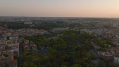 Forvetler Oppian Hill parkının üzerinde tarihi işaretlerle uçuyor. Antik Colosseum amfitiyatrosuna doğru gidiyor. Gün batımında şehrin panoramik manzarası. Roma, İtalya.