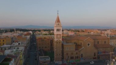 Kare kulesi olan kilisenin havadan yükselen görüntüleri. Alacakaranlıkta konut binaları ile kentsel ilçeleri gözler önüne sermek. Roma, İtalya.