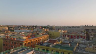 Şehir merkezindeki apartmanların üzerinden altın saat uçuyor. Trenlerin çok raylı demiryolu hattında yavaşça ilerlediğini gösteriyor. Roma, İtalya.