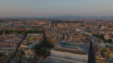 Şehir merkezinde günbatımında forvetler klasik şehir gelişiminin üzerinde uçar. Esquilino ilçesindeki sokaklar ve binalar. Roma, İtalya.