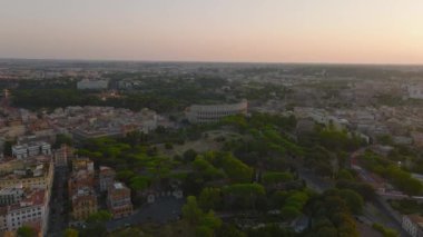 Antik Kolezyum amfitiyatrosunun ve tarihi şehir merkezindeki tarihi park ve binaların hava kaydırak ve pan görüntüleri. Roma, İtalya.