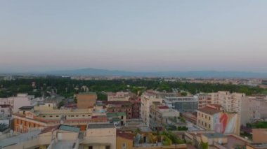 Alacakaranlıkta şehirdeki apartmanların üzerinde alçak uçuş. Verano Anıtsal Mezarlığı ile büyük bir parkı gözler önüne sermek. Roma, İtalya.