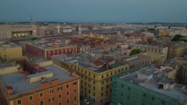 Alacakaranlıkta şehirdeki binaların üzerinden ileriye doğru uçar. Roman Terminali tren istasyonuna yaklaşan modern yüksek hızlı tren ünitesi ortaya çıkıyor. Roma, İtalya.