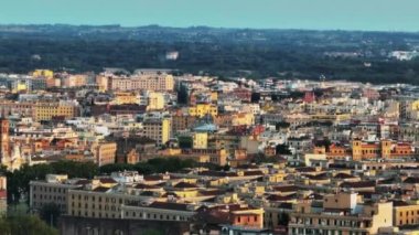 Şehrin üstünden uç. Şehir merkezindeki apartmanların havadan çekilmiş görüntüleri alçak güneş tarafından aydınlatılıyor. Roma, İtalya.