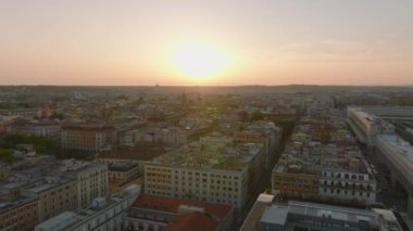 Esquilino ilçesindeki şehir merkezinin üzerinde ilerliyorlar. Büyük şehirde gün batımına karşı düz manzaralı binalar. Roma, İtalya.