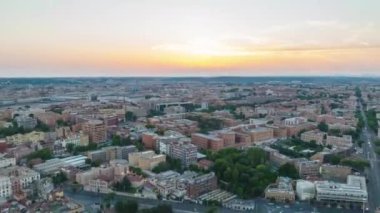 Şehir merkezindeki çok katlı binaların üzerinde ilerliyorlar. Gün batımında yüksek hızda çekim. Roma, İtalya.