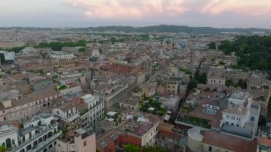 Parktaki yeşil ağaçlar arasındaki güzel tarihi bina ve arka planda bulutlu bir günde şehirdeki binalar. Borghese Galerisi. Roma, İtalya.