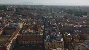 Forvetler tarihi şehir merkezindeki eski apartman evlerinin üzerinden uçuyor. Altın saatinde çatı terasları olan çok katlı binalar. San Carlo al Corso Bazilic kulesine gidiyoruz. Roma, İtalya.