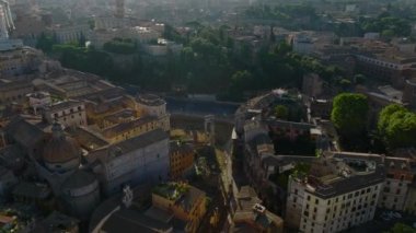 Alacakaranlıkta şehir merkezindeki binaların üzerinden uç. Kentsel alanda çeşitli eski konutlar. Diğer çatıların üzerinde yükselen kilise kuleleri. Roma, İtalya.