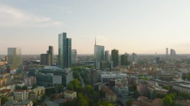 İleri, şehrin üzerinde uçar. Lombardy Binası 'nın etrafındaki bir grup modern binaya doğru gidiyor. Milano, İtalya