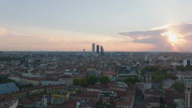 İleri uçaklar şehir merkezinin üzerinde. Günbatımında gökyüzüne karşı modern gökdelenlerden oluşan bir grup siluet. Milano, İtalya.