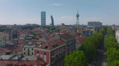 Yeşil ağaçlarla kaplı caddenin üzerinde uç. Şehir merkezindeki apartmanlar. Modern ofis kuleleri. Milano, İtalya.