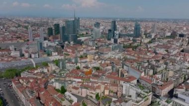 Şehir merkezinin üzerinde ilerliyorlar. Şehir merkezindeki bir grup modern ofis kulesine doğru gidiyor. Milano, İtalya.
