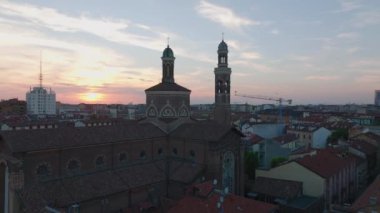 Kuleleri olan eski tuğla kilisenin hava kaydırak ve pan görüntüleri. Şehir merkezindeki dini yapı, günbatımının gökyüzüne karşı. Milano, İtalya.