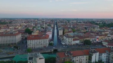 Önler kalabalık caddenin üzerinde arabalar ve tramvaylarla uçar. Tarihsel su kanalı Naviglio Pavese şehir gelişimine öncülük ediyor. Milano, İtalya.