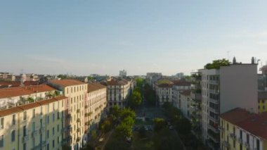 İleride ağaçlar ve sıra sıra apartman daireleri var. Kasaba inşaatı altın saatinde. Milano, İtalya.