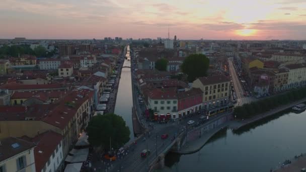 在日落的天空下 沿着水渠和周围建筑物的繁忙的海滨的空中下降镜头 意大利米兰 — 图库视频影像