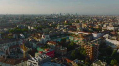 Altın saatinde şehir merkezindeki binaların üzerinden uç. Uzaktaki modern yüksek binalardan oluşan bir grup. Milano, İtalya.