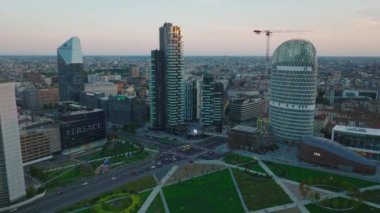 Alacakaranlıkta şehir merkezindeki modern tasarım yüksek katlı ofis binalarının havadan görünüşü. Yol kavşağındaki trafiği azalt. Milano, İtalya.