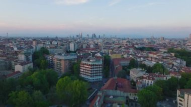 Gün batımında Metropolis 'in havadan yükselen görüntüleri. Kentsel ilçelerdeki şehir gelişimi ve arka plandaki modern yüksek katlı ofis binaları. Milano, İtalya.